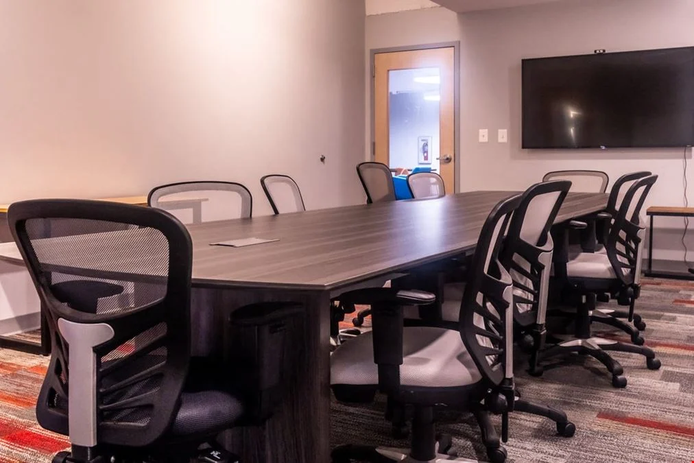 A long conference table, office chairs and wall-mounted screen at The Cube Cowork.